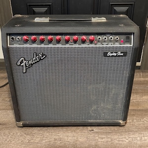 May include: Black Fender Eighty-Five guitar amplifier with a gray speaker cover. The amplifier has red knobs and the Fender logo in silver. The text "Eighty Five" is printed on the speaker cover.