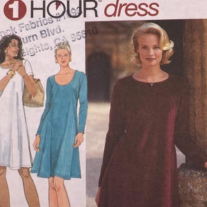 Può includere: Una busta per cartamodello Simplicity 9897 per un abito 1 Hour. Il fronte presenta illustrazioni di quattro varianti di abiti: un abito floreale senza maniche, un abito bianco a maniche corte, un abito blu e un abito bordeaux a maniche lunghe.