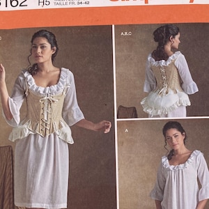Puede incluir: Patrón de costura Simplicity 8162 para un corpiño y vestido. El sobre muestra ilustraciones de un corsé beige con cordones y un vestido blanco con mangas y escote con volantes. Incluye información de tallas europeas 34-42 y la marca American Duchess.