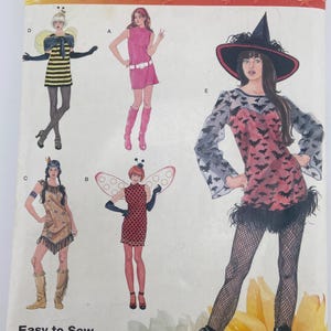May include: Simplicity costume pattern for adults, featuring illustrations of various Halloween costumes. The cover displays a witch costume, a bee costume, a fairy costume, and other designs. The pattern includes sizes XS to XL.