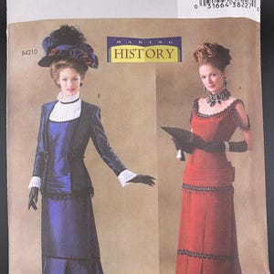 May include: Butterick sewing pattern B4212 featuring two women in historical dresses. One woman wears a navy blue outfit with a matching hat, and the other wears a red dress. The pattern includes the text "MAKING HISTORY".
