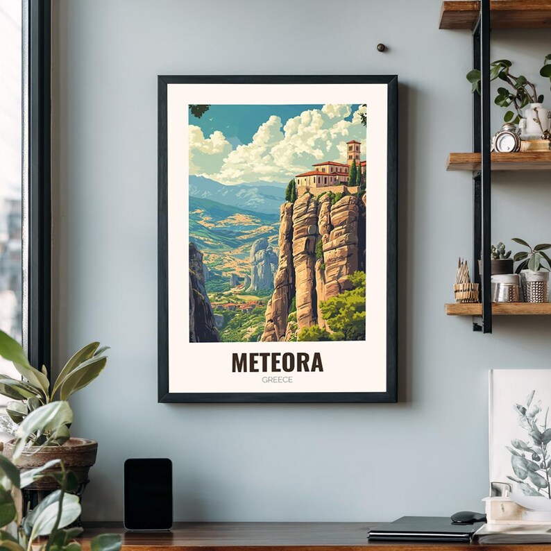 May include: Framed art print showcasing Meteora, Greece. The image displays a monastery perched on a high rock, with a colourful landscape of mountains and valleys. The print is in a black frame, and the word "METEORA" is printed at the bottom.