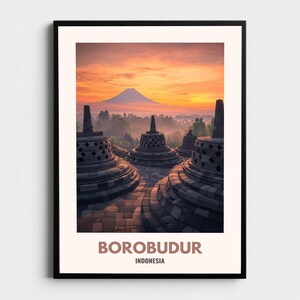 Könnte beinhalten: Gerahmter Druck mit dem Borobudur-Tempel in Indonesien. Das Bild zeigt die einzigartigen Stupas des Tempels und einen Berg im Hintergrund, vor einem leuchtend orange-gelben Himmel. Der Text "BOROBUDUR INDONESIA" ist unten zu sehen.