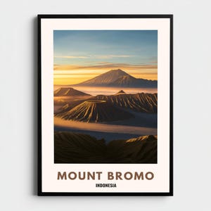 Op de afbeelding: Een ingelijste print met een schilderachtig uitzicht op Mount Bromo in Indonesië. De afbeelding toont een bergketen met een levendige lucht in oranje en blauwe tinten. De tekst "MOUNT BROMO" en "INDONESIA" staat in bruin onderaan.