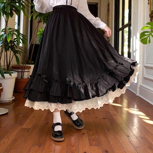 以下が含まれることがあります： 黒色のティアードスカート、フリルと白いレースの裾が特徴です。 スカートは黒いメリージェーンシューズと白い靴下と組み合わせています。 この服装はクラシックでエレガントなスタイルです。