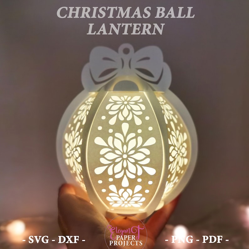 May include: A white Christmas ball lantern with intricate floral cutouts, topped with a bow. The lantern is illuminated from within, creating a warm glow. Text on the image reads "CHRISTMAS BALL LANTERN", "- SVG - DXF -", and "- PNG - PDF -".