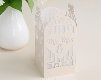 May include: A cream-colored paper lantern template with intricate cut-out designs, including a heart with "Mr Mrs &" text. The lantern has a rectangular shape with arched top details. The text "LANTERN TEMPLATE" is at the top. The bottom has "SVG - DXF -" and "- PNG - PDF -" text.
