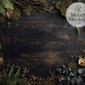May include: Dark wood background with a natural, rustic aesthetic. The image features a variety of green ferns, moss, and dried plants arranged around the edges. A circular logo with the text "Moody Mockups co." is visible.