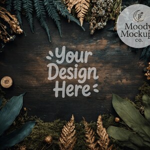 May include: A dark wood surface surrounded by green and gold foliage, moss, and dried plants. The text "Your Design Here" is in the center, with a circular logo that reads "Moody Mockups co." in the upper right corner.