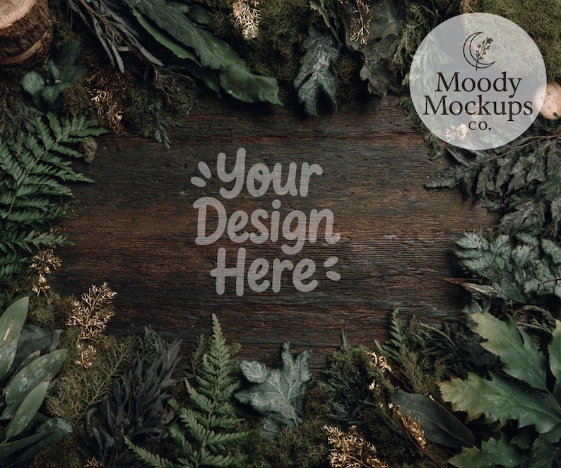 May include: A rustic wooden surface surrounded by green foliage, ferns, and moss. The text "Your Design Here" is displayed in a light font. A circular logo with the text "Moody Mockups Co." is in the upper right corner.