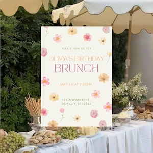 Peut inclure: Une invitation de brunch avec des accents floraux. L'invitation indique "Brunch d'anniversaire d'Olivia" avec la date et l'heure. L'invitation est ornée de fleurs aquarelles roses et jaunes. L'invitation est sur une table avec de la nourriture et des boissons.