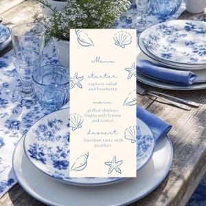 Pode incluir: Uma mesa posta com pratos, copos e um menu com motivos florais azuis e brancos. O menu inclui salada caprese e bruschetta, coxas de frango grelhadas e tarte de avelã com pêssegos. A mesa está pronta para uma refeição.