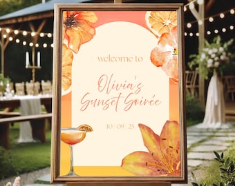 May include: A framed sign on an easel with the text "welcome to Olivia's Sunset Soiree" in a script font. The sign features watercolor illustrations of orange flowers, orange slices, and a cocktail. The date "10|09|25" is displayed.