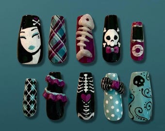 May include: A collection of ten press-on nails with various designs. The designs include a crying woman, plaid, a fish skeleton, a skull with a bow tie, a retro phone, a diamond pattern, ruffles, a rib cage, polka dots, and a skull with swirls.