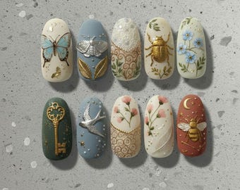 Puede incluir: Diez uñas ovaladas pintadas a mano con diseños únicos. Las uñas presentan mariposas, polillas, llaves, flores e insectos en oro, azul, verde y blanco. Se aprecian detalles y texturas intrincadas en cada uña.