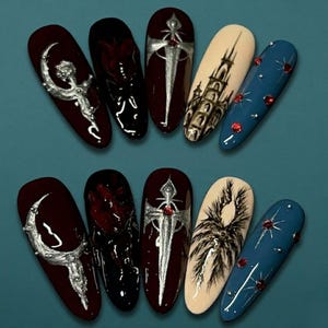 May include: A set of ten long, oval-shaped artificial nails with various gothic-inspired designs. The nails feature dark red, black, and beige bases, adorned with silver and red accents, including a crescent moon, a sword, and a castle.