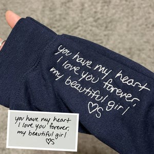 May include: Navy blue fabric with white embroidered text: "you have my heart, I love you forever, my beautiful girl" and a heart symbol. A small card with the same text is also visible.