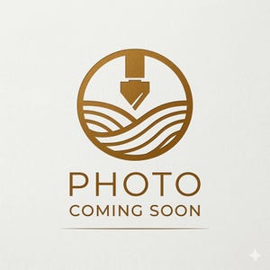 May include: A circular gold logo featuring a stylized fountain pen nib pointing downward toward wavy lines, positioned above the text "PHOTO COMING SOON" in a clean, sans-serif font. The design is rendered in a metallic gold color.