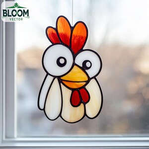 Może przedstawiać: Witryna z kogutem o fantazyjnym wzorze. Kogut ma białe, pomarańczowe, czerwone i żółte szkło, obrysowane na czarno. Logo Bloom Vector znajduje się w lewym górnym rogu. Kogut wisi przed oknem.
