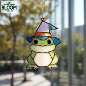 Könnte beinhalten: Ein Buntglasfrosch mit Hexenhut. Der Frosch ist grün, weiß und hellgrün mit schwarzen Augen. Der Hut ist lila, blau und orange. Das Bloom Vector-Logo befindet sich oben links.