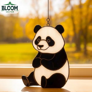May include: A stained glass panda bear suncatcher with black and white coloring. The panda is sitting with its legs crossed. The suncatcher is hanging from a chain. The Bloom Vector logo is in the upper left corner.