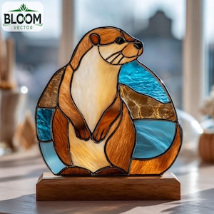 Pode incluir: Estatueta de lontra em vitral com tons de castanho, bege e azul. A lontra é montada numa base retangular de madeira. O logotipo Bloom Vector está no canto superior esquerdo.