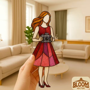 May include: A paper cutout of a woman in a red dress holding a camera. The dress is a patchwork of red and pink hues. The woman has flowing red hair and is wearing red heels. The image has a Bloom Vector logo in the bottom right corner.