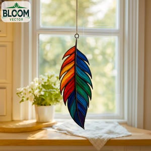 Pode incluir: Um apanhador de sol de pena de vitral colorido. A pena é dividida em seções de vermelho, laranja, amarelo, verde e azul. Ele pende de uma corrente dourada. O logotipo Bloom Vector é visível.