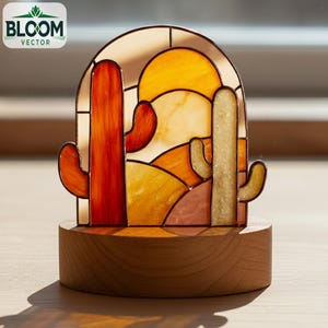 Op de afbeelding: Gebrandschilderde cactusscène in warme kleuren, oranje, geel en bruin, op een houten voet. Het Bloom Vector-logo is linksboven zichtbaar. Het kunstwerk toont een woestijnlandschap.