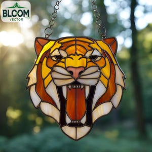 May include: A stained glass tiger head suncatcher with a fierce expression. The tiger's face features shades of yellow, orange, and brown, with white and black accents. The suncatcher is suspended by a metal chain and features the Bloom Vector logo.