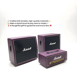 Könnte beinhalten: Drei Marshall-Verstärker in einem Studio. Die Verstärker sind tiefviolett mit schwarzen Lautsprecherabdeckungen und dem Marshall-Logo in Weiß. Der Text im Bild lautet: "Hergestellt aus langlebigen, hochwertigen Materialien. Verleiht jedem Raum oder Studio einen stilvollen Touch."