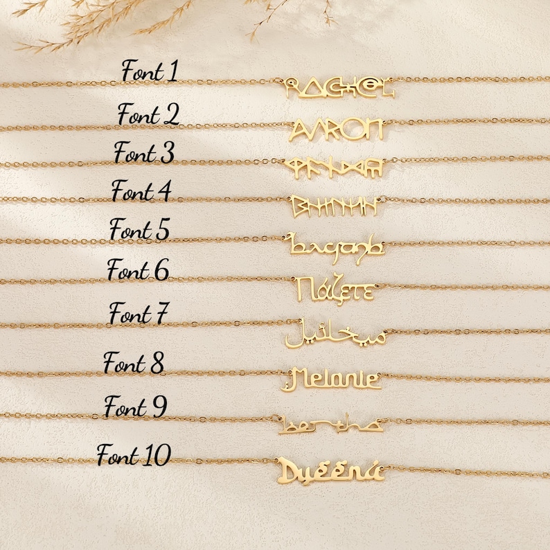 Puede incluir: Collares dorados con varios nombres en diferentes fuentes. Los nombres incluyen Rachel, Aaron y Melanie. La imagen tambi&eacute;n muestra el texto "Font 1" a "Font 10". Los collares se exhiben sobre una superficie clara.