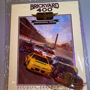 May include: A program for the Brickyard 400 Inaugural Race, featuring a colorful illustration of race cars on the track. The program is in a clear plastic sleeve. The text includes "Indianapolis Motor Speedway" and "Official Program".