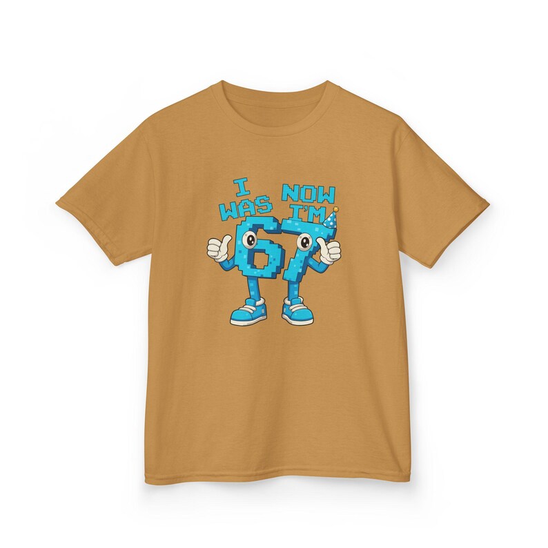 Pu&ograve; includere: T-shirt color senape con una grafica a cartoni animati dei numeri "67" con braccia, gambe e scarpe. I numeri hanno dettagli pixelati blu e la scritta "I WAS NOW I'M" in blu sopra. Un cappello da festa &egrave; sul numero 7.