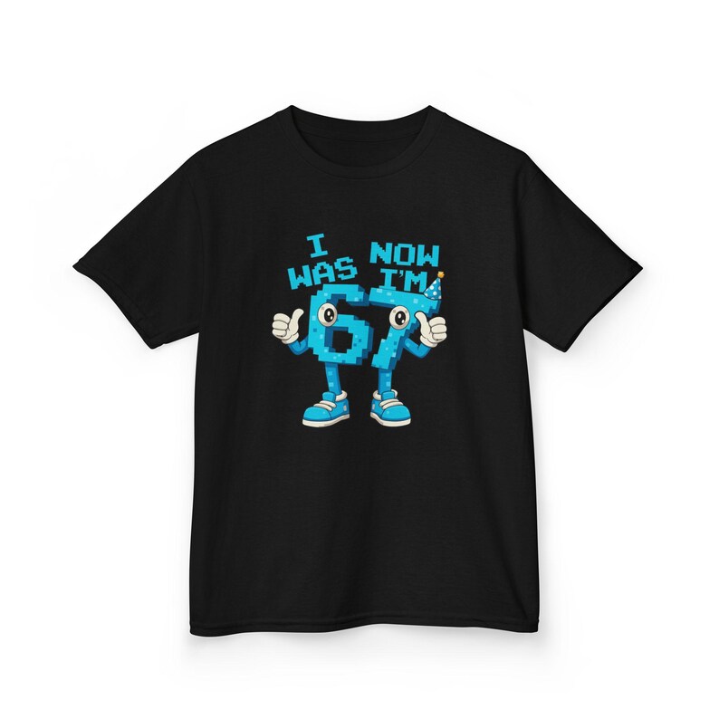 Pu&ograve; includere: T-shirt nera con una grafica del numero 67 come un personaggio dei cartoni animati con braccia, gambe e scarpe. Il testo sopra il numero recita "I WAS 67 NOW I'M". Il numero &egrave; azzurro con dettagli bianchi e un cappello da festa.