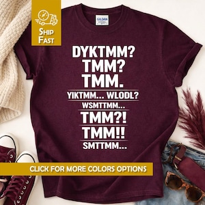 May include: A maroon Gildan t-shirt with white text that reads "DYKTMM? TMM? TMM. YIKTMM... WLODL? WSMTTMM... TMM?! TMM!! SMTTMM...". The shirt also has a "Click for more colors options" button.
