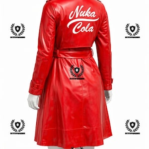 Pode incluir: Um trench coat vermelho brilhante com cinto, com o texto branco "Nuka Cola" nas costas. O casaco tem um design clássico com gola e botões. A imagem mostra a parte de trás do casaco em um manequim.