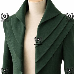May include: A dark green coat with a unique layered collar design. The coat is displayed on a mannequin, showcasing its tailored fit and structured silhouette. The coat's color is a deep, forest green, and the fabric appears to be a soft wool or similar material.