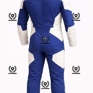 May include: A blue and white racing suit with a full-length zipper. The suit features white panels on the shoulders, arms, and legs, contrasting with the blue fabric. The back view shows the suit's design and stitching.