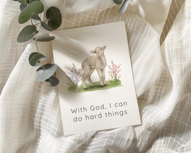 May include: A rectangular greeting card featuring a watercolor illustration of a small lamb standing in a patch of green grass with colorful wildflowers. The text "With God, I can do hard things" is printed in black below the illustration.