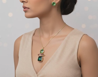 May include: A gold necklace with a pendant featuring a green square and oval gemstone, and a pink gemstone. Matching green stud earrings are also visible. The jewelry is set against a neutral background.