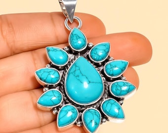 May include: A silver pendant featuring a large, teardrop-shaped turquoise stone at the center, surrounded by smaller turquoise teardrops. The pendant has a silver bail for a chain. The turquoise stones have dark blue veining.