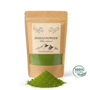 Könnte beinhalten: Ein Kraftpapierbeutel mit Indigo-Pulver, wobei grünes Pulver durch ein transparentes Fenster sichtbar ist. Das Etikett lautet "INDIGO POWDER (Ribes nigrum)" über einer Berg-Grafik und "THE DESI SPICES". Ein Haufen grünes Pulver liegt vor dem Beutel.