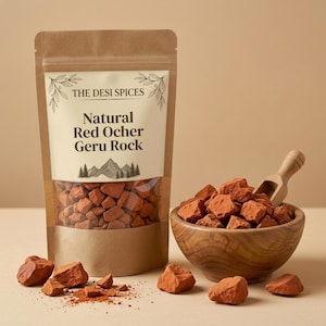 Könnte beinhalten: Ein brauner Papierbeutel mit der Aufschrift THE DESI SPICES Natural Red Ocher Geru Rock, der kleine rotbraune Mineralstücke enthält. Daneben steht eine Holzschale mit denselben roten Ockersteinen und einer kleinen Holzschaufel, mit verstreuten Stücken.