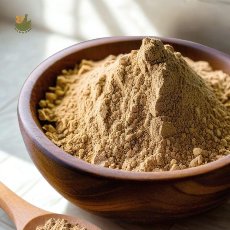 May include: A wooden bowl filled with a light brown powder, possibly a spice or herb. The bowl is made of a dark wood and has a smooth, polished finish. A wooden spoon with the same powder is in the foreground. The image is well-lit, highlighting the texture of the powder.