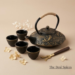 May include: A black cast iron teapot with a rope handle, four matching cups, and a tea utensil. The teapot has a decorative design and is accompanied by dried flowers. The set is designed for tea service.