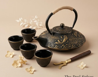 Puede incluir: Una tetera de hierro fundido negro con un asa de cuerda, cuatro tazas a juego y un utensilio para el té. La tetera tiene un diseño decorativo y está acompañada de flores secas. El juego está diseñado para el servicio de té.