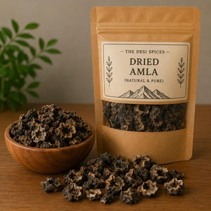 Puede incluir: Una bolsa de papel marrón de amla seca con una ventana transparente, junto a un cuenco de madera lleno de amla seca. La bolsa tiene una etiqueta que dice "Dried Amla (Natural & Pure)" con un gráfico de montaña. La amla es de color marrón oscuro y en forma de estrella.