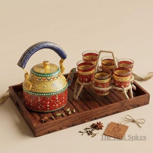 Peut inclure: Un service à thé décoratif avec une théière peinte à la main, une poignée bleue et un plateau assorti avec six verres. La théière est jaune, rouge et verte avec des motifs floraux. Les verres sont rouges et jaunes avec un motif décoratif.