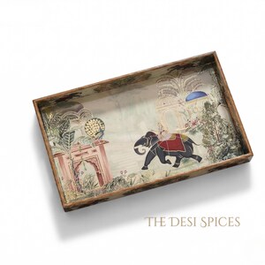 May include: Rectangular wooden serving tray with an Indian-inspired design. The tray features a painted scene of an elephant carrying a person, set against a backdrop of architectural elements and lush greenery. The tray's border has a dark brown finish.